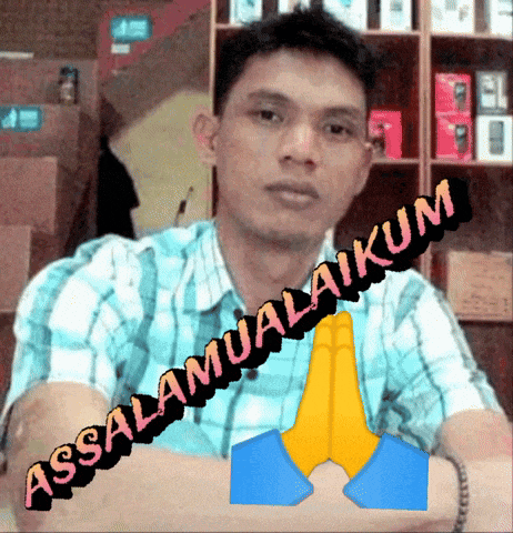 a man in a plaid shirt is sitting in front of a sign that says " assalamualaikum "