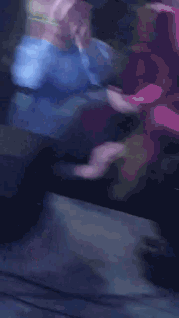a blurry picture of a man in a blue shirt with his hands in the air