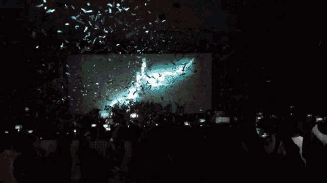 a crowd of people at a concert with confetti falling in front of a screen that says ' nirvana ' on it