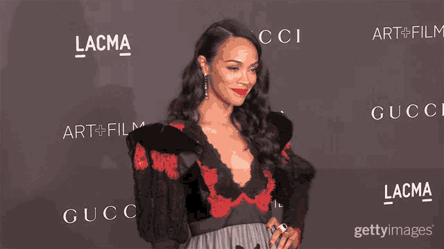 a woman stands on a red carpet in front of a wall that says lacma and gucci