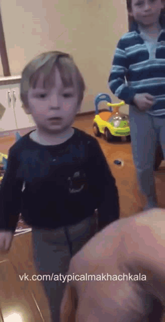 a little boy is standing in front of a yellow toy car with the website vk.com/atypicalmakkachkala written below him