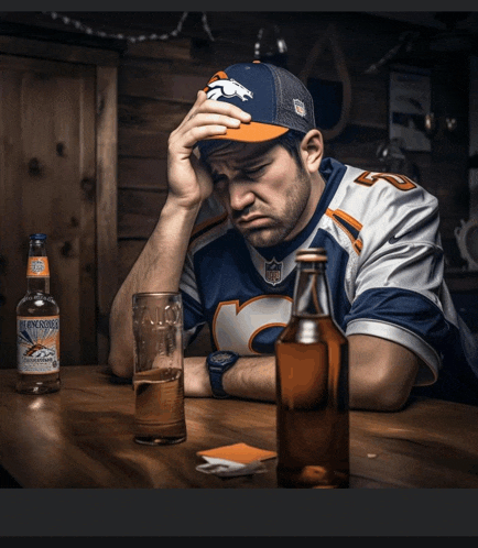 a man wearing a broncos jersey is sitting at a table