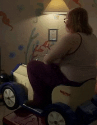 a woman is sitting in a small toy car in a room .