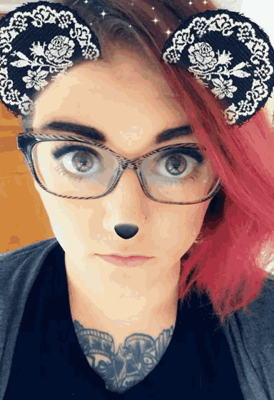 a woman with pink hair wearing glasses and a cat ear headband