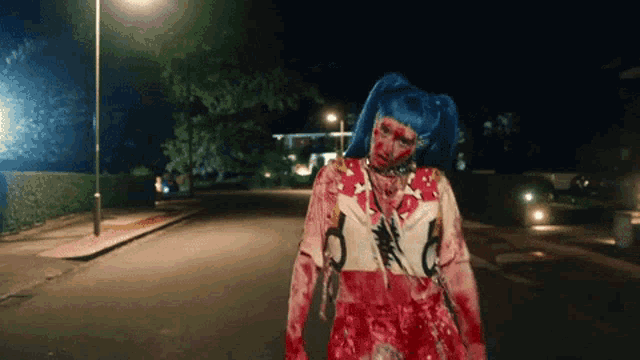 a woman with blue hair is walking down a street with blood on her clothes