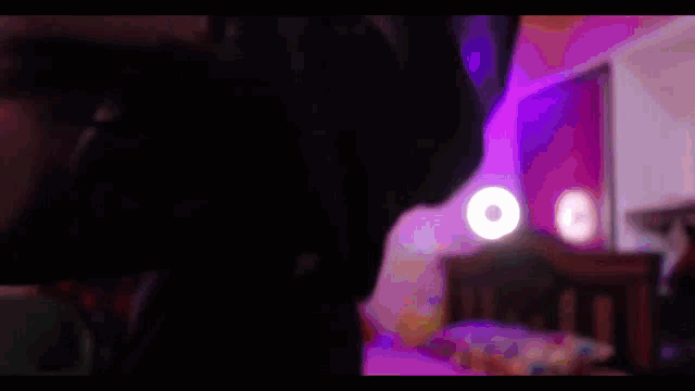 a man is holding a woman in his arms in a dark room with purple lights
