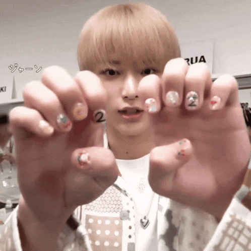 a man with blonde hair shows off his nails with the number 2 on them