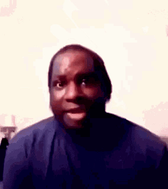 a man in a blue shirt is making a funny face while giving the middle finger .
