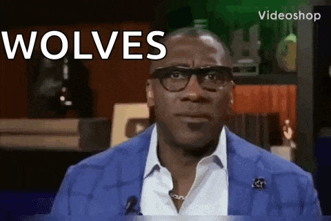 a man wearing glasses and a blue suit is talking into a microphone and says wolves .