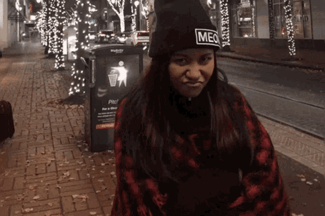 a woman wearing a black beanie that says meq