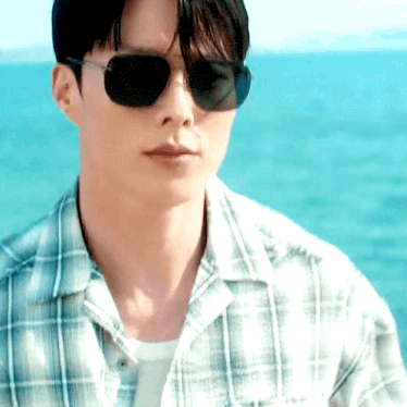 a man wearing sunglasses and a plaid shirt is looking at the camera