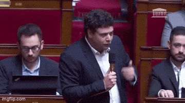 a man in a suit is speaking into a microphone in a parliament .