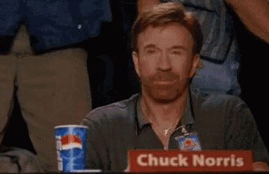 a man sitting at a table with a sign that says " chuck norris "