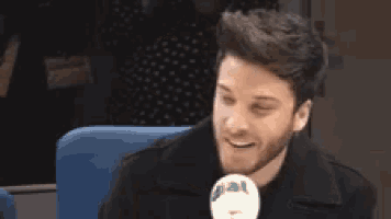 a man with a beard is sitting in a chair with a microphone in front of him .