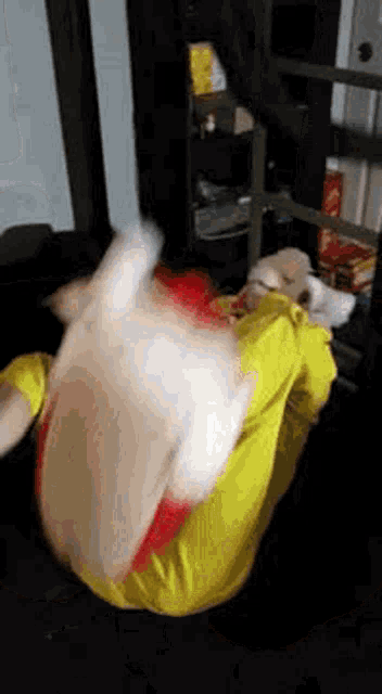 a person in a yellow shirt is laying on their stomach with a stuffed animal .