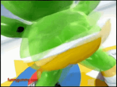 a close up of a green and yellow cartoon character with the website funnygummy.com written below it