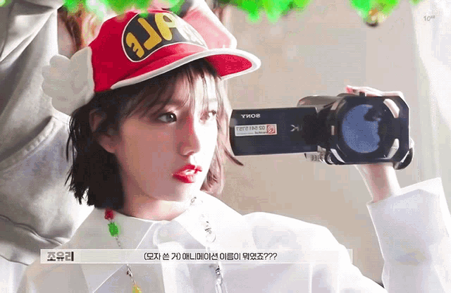 a woman wearing a red hat with the letter j on it holds a video camera