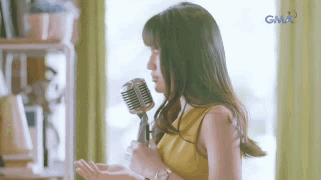 a woman singing into a microphone with gma in the corner