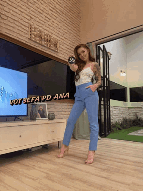 a woman stands in front of a television with the words voi sefa pd ana written on the screen