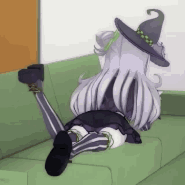 a witch laying on a green couch with her legs crossed
