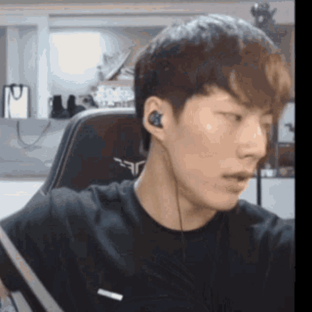 a young man wearing headphones is sitting in a chair in front of a computer screen .