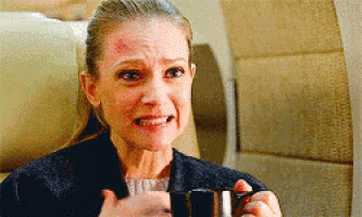 a woman is holding a cup of coffee and making a funny face .