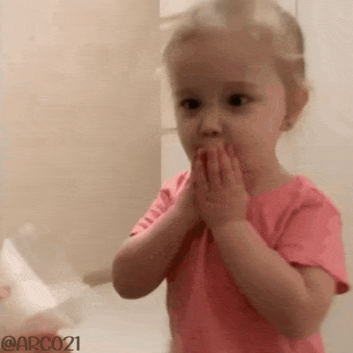 a little girl is brushing her teeth in front of a mirror .