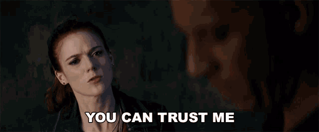 a woman says you can trust me while looking at a man in a dark room