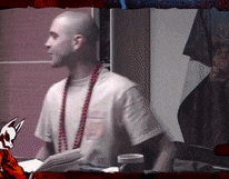 a bald man wearing a white shirt and red beads is sitting at a table