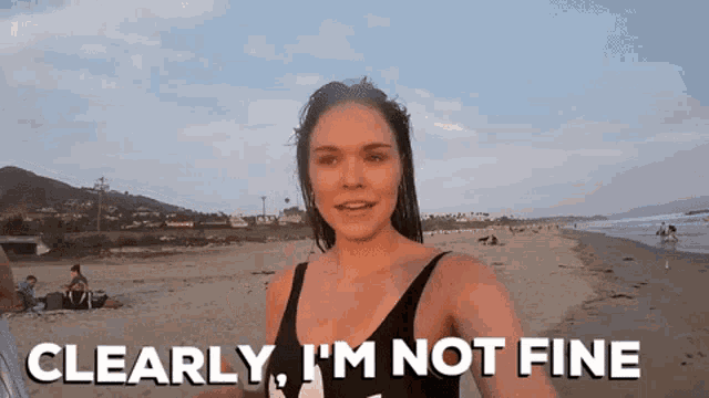 a woman standing on a beach with the words clearly i 'm not fine below her