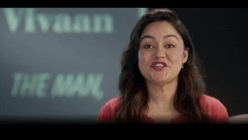 a woman is making a face in front of a sign that says vivaan the man