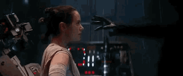 a woman is standing next to a robot in a dark room and looking at it .