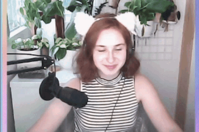 a woman wearing headphones and a cat ear headband is sitting in front of a microphone .