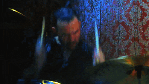 a man is playing drums in front of a wall