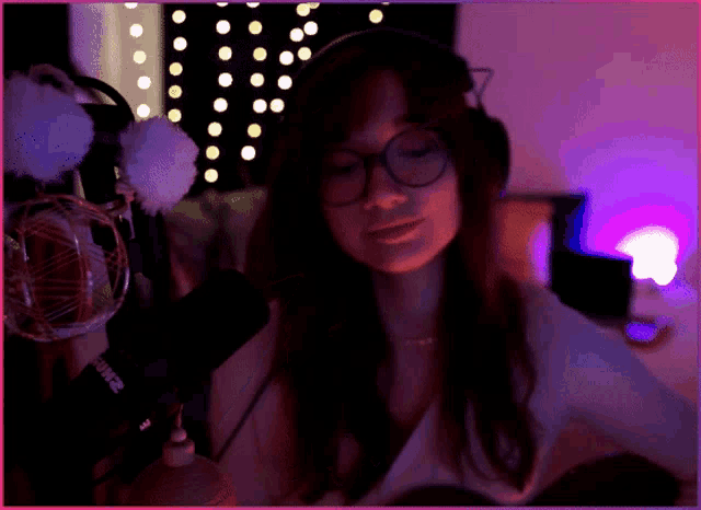 a woman wearing glasses and headphones stands in front of a microphone that says shure