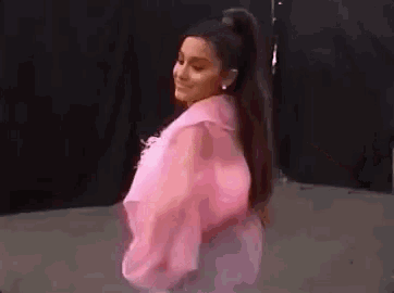 ariana grande is wearing a pink jacket and a pink ponytail .