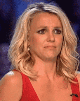 a woman with blonde hair and a red dress is making a sad face .