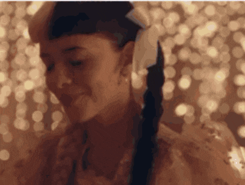 a close up of a woman 's face with a braid and a ponytail .