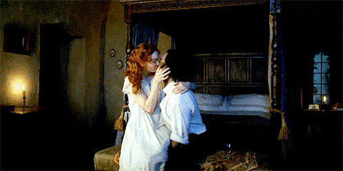 a man and a woman are kissing in a dark room