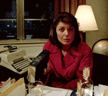a woman sitting at a desk holding a book that says ' dictionary ' on the cover