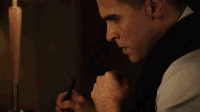 a man sits at a table with his hands folded over a book