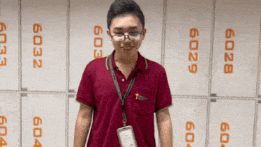 a man wearing glasses and a lanyard stands in front of lockers with the numbers 6029 and 6034