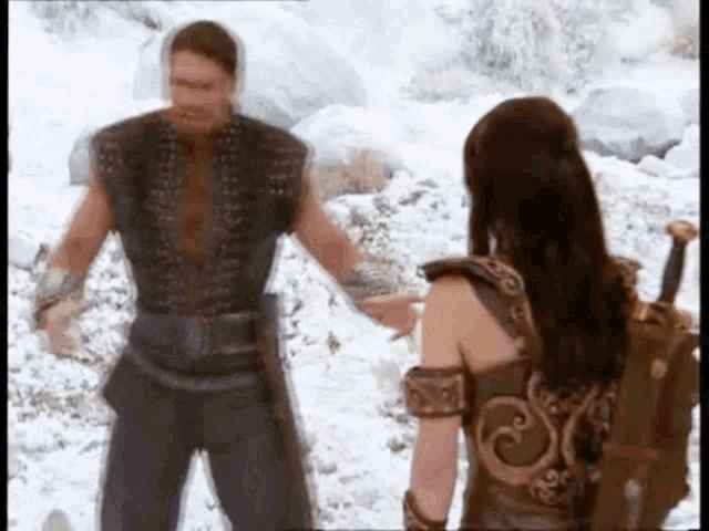 a man and a woman are standing in the snow holding hands .