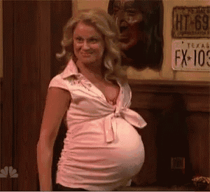 a pregnant woman in a pink shirt is standing in front of a texas license plate