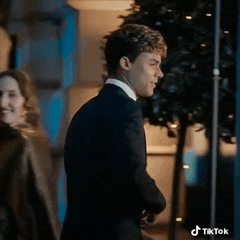 a man in a suit and tie is standing next to a woman in a coat .