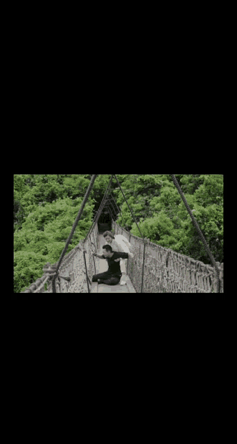 a couple laying on a bridge over a lush green field