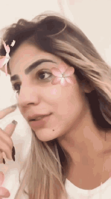 a woman with a flower on her face looks at the camera