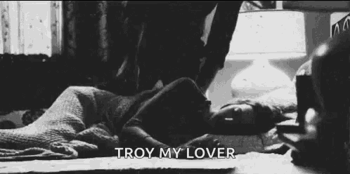a black and white photo of a woman laying on the floor with the words troy my lover above her