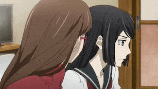 two anime girls are sitting next to each other in a living room .