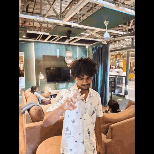 a man in a white shirt is giving the peace sign in a living room